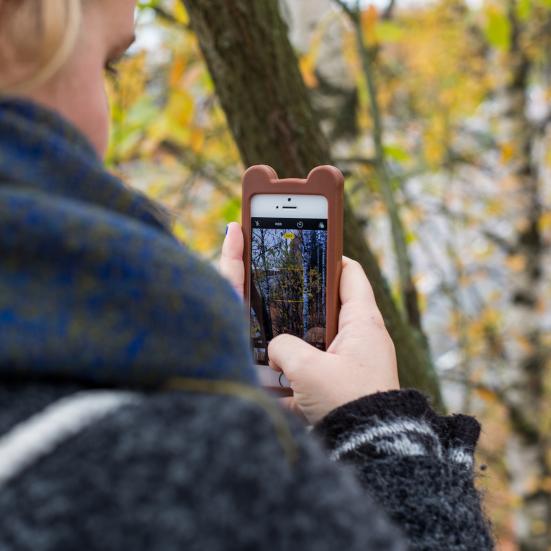 Pige der tager billeder med sin mobil i naturen