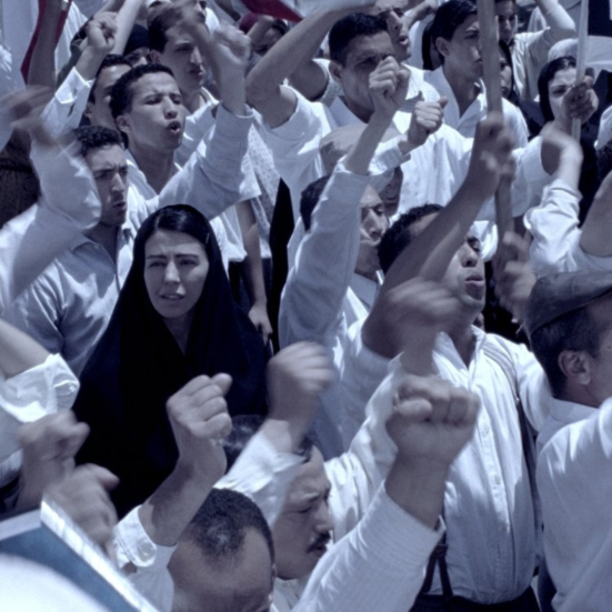 kvinde med tørklæde i sort til demonstration med en masse mænd i hvidt