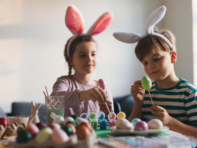 2 børn med kaninører maler påskeæg