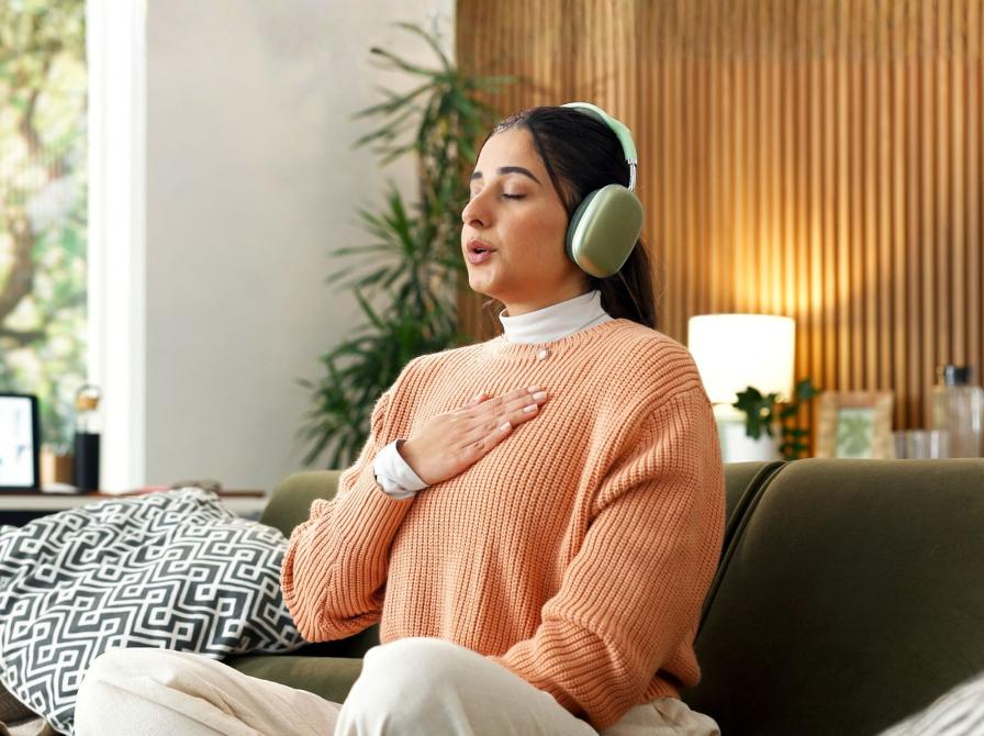 Person med hovedtelefoner mediterer i en sofa.