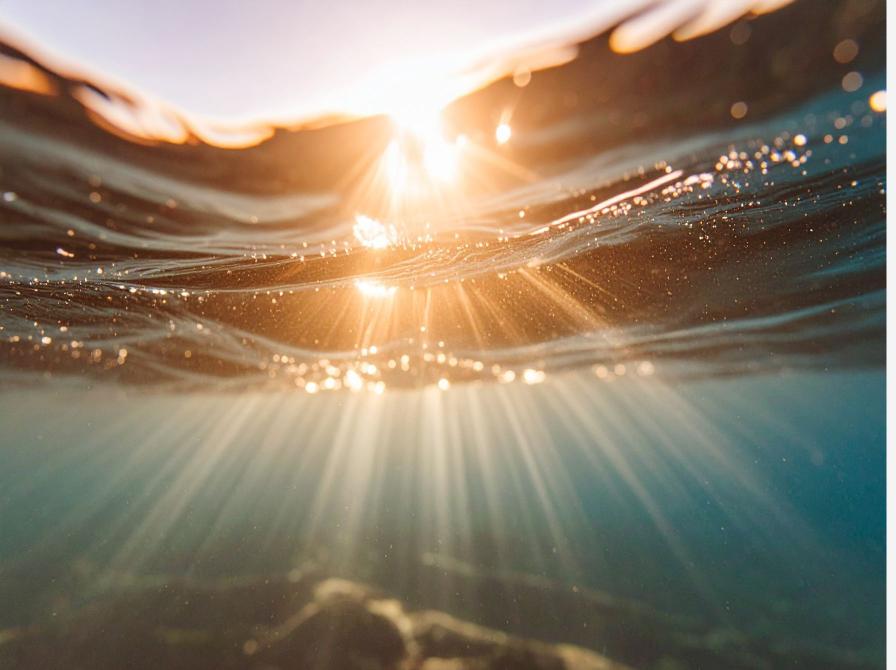 Solstråler bryder overfladen på vand
